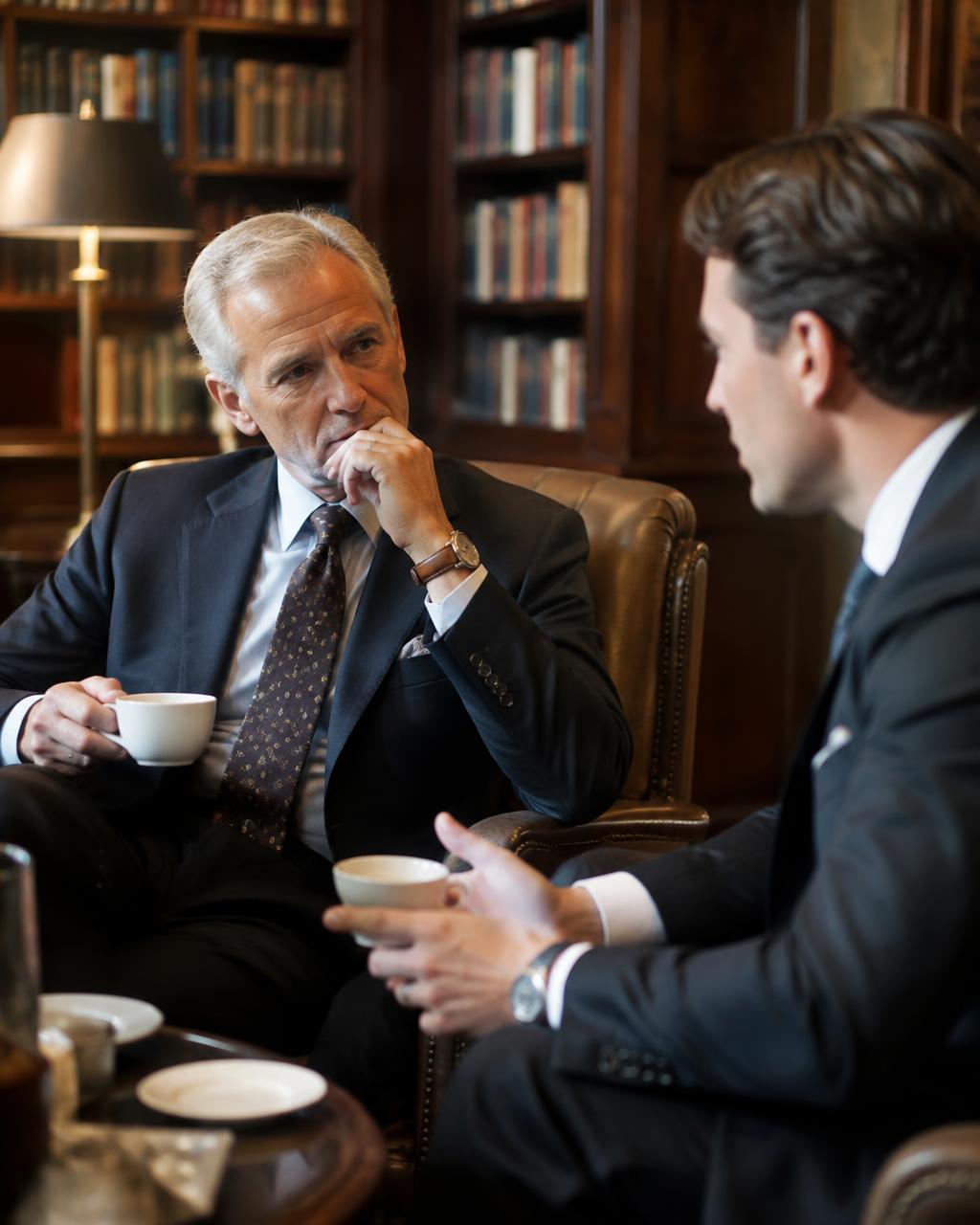 Two professionals of different generations in conversation in a library